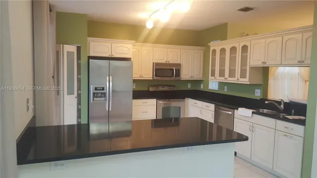 a kitchen with white cabinets and black appliances