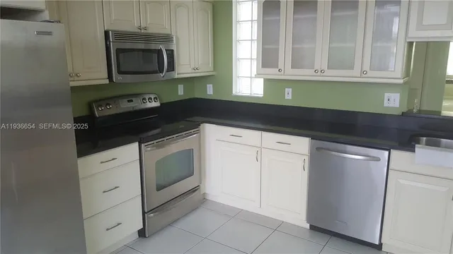 a kitchen with white cabinets and black appliances