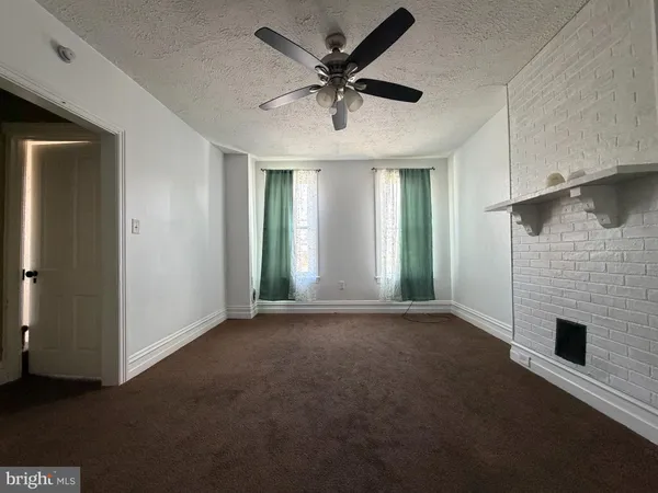 an empty room with windows and ceiling fan
