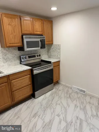 a kitchen with granite countertop a stove top oven microwave and cabinets
