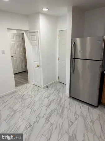 a view of empty room with wooden floor and refrigerator