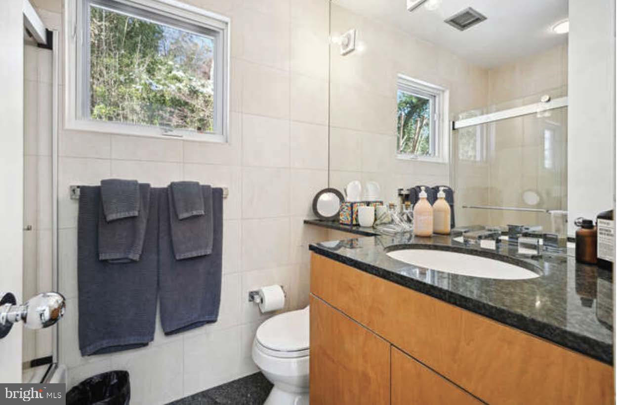 4527 Q Place Northwest Washington, DC 20007 - Photo 23 of 54 a bathroom with a granite countertop toilet sink and mirror