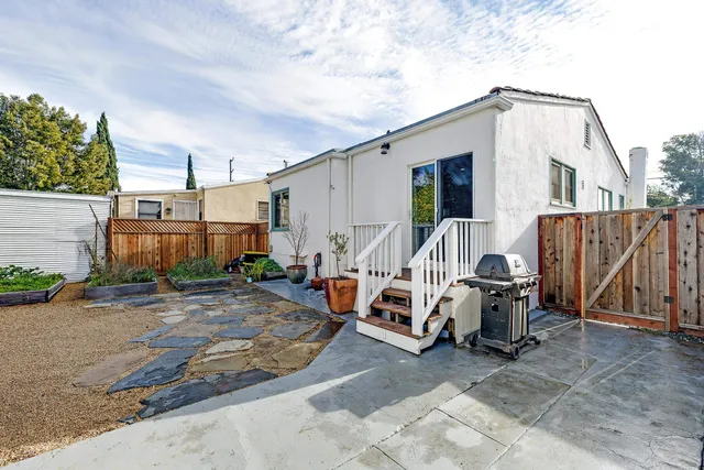 a view of backyard with seating space and trees in the background