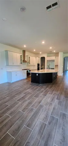 a large room with kitchen island stainless steel appliances wooden floors and view living room