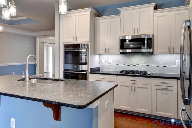 a kitchen with stainless steel appliances a sink a stove and cabinets
