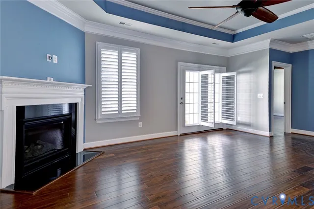 a view of an empty room with wooden floor fireplace and a window