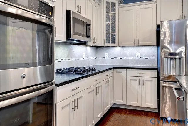 a kitchen with stainless steel appliances granite countertop a refrigerator and white cabinets