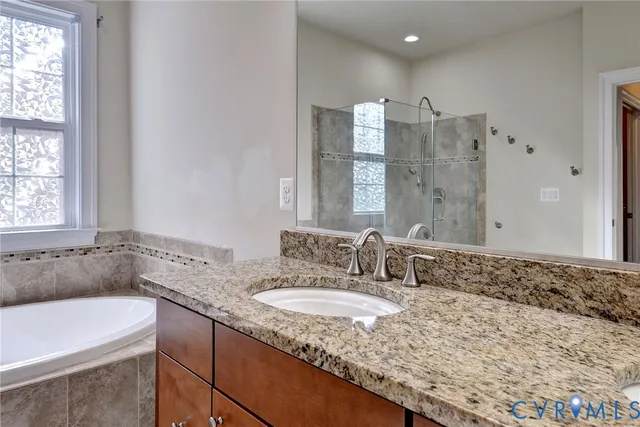 a bathroom with a granite countertop bathtub sink vanity and mirror