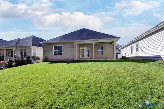 a view of a yard in front of a house with plants and large tree