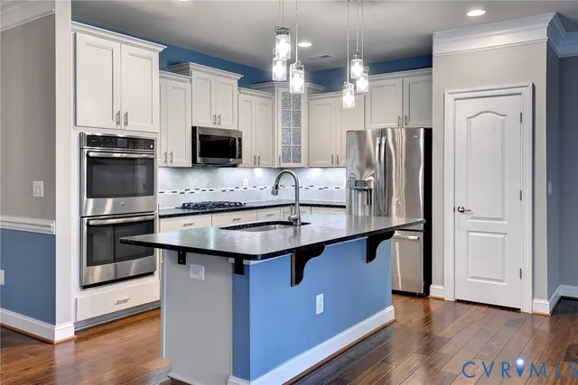 a kitchen with stainless steel appliances kitchen island granite countertop a refrigerator and a sink