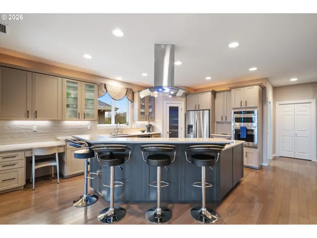 a kitchen with stainless steel appliances granite countertop a table chairs sink and stove