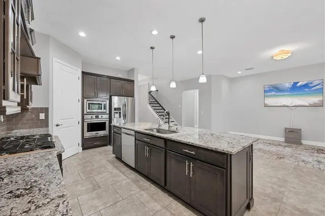 a large kitchen with stainless steel appliances kitchen island granite countertop a large counter top and a refrigerator