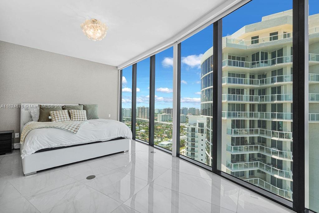 18555 Collins Avenue, Unit 2605 Sunny Isles Beach, FL 33160 - Photo 12 of 22 a bedroom with a large bed and a large window with outer view