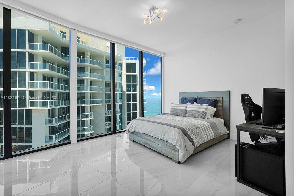 18555 Collins Avenue, Unit 2605 Sunny Isles Beach, FL 33160 - Photo 15 of 22 a spacious bedroom with a bed and glass door