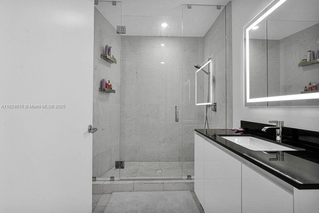 18555 Collins Avenue, Unit 2605 Sunny Isles Beach, FL 33160 - Photo 16 of 22 a bathroom with a granite countertop sink a shower and a mirror