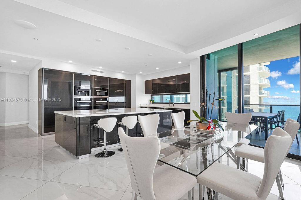 18555 Collins Avenue, Unit 2605 Sunny Isles Beach, FL 33160 - Photo 5 of 22 a dining hall with stainless steel appliances kitchen island granite countertop a dining table chairs and a living room view