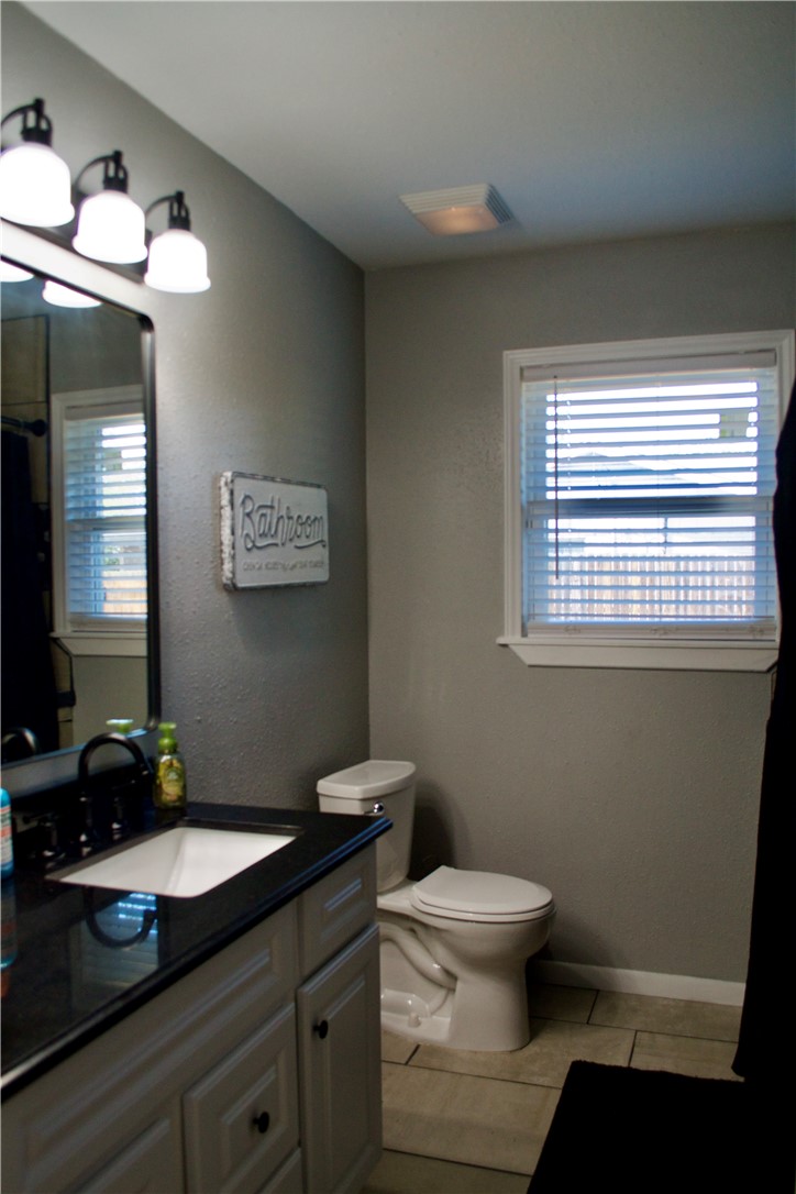 1001 East Hefferman Street Beeville, TX 78102 - Photo 11 of 12 a bathroom with a granite countertop sink mirror vanity and a toilet