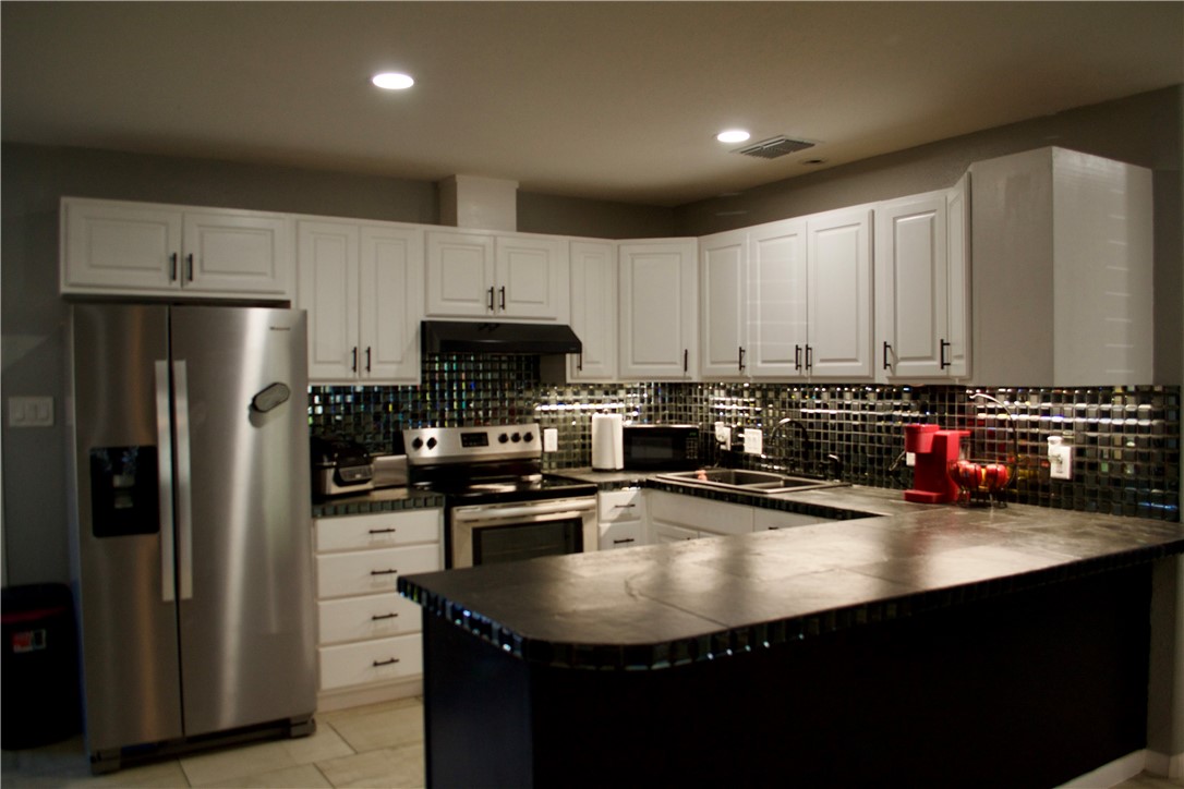 1001 East Hefferman Street Beeville, TX 78102 - Photo 4 of 12 a kitchen with kitchen island a sink stainless steel appliances and cabinets