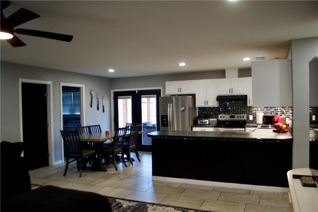 1001 East Hefferman Street Beeville, TX 78102 - Photo 6 of 12 a kitchen with stainless steel appliances granite countertop a stove top oven a sink dishwasher a dining table and chairs with wooden floor