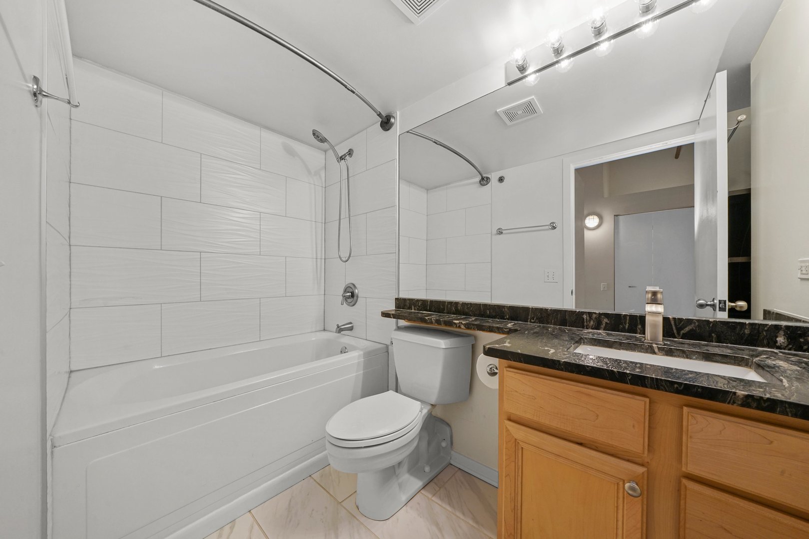 500 South Clinton Street, Unit 424 Chicago, IL 60607 - Photo 14 of 29 a bathroom with a granite countertop bathtub shower sink vanity mirror and toilet