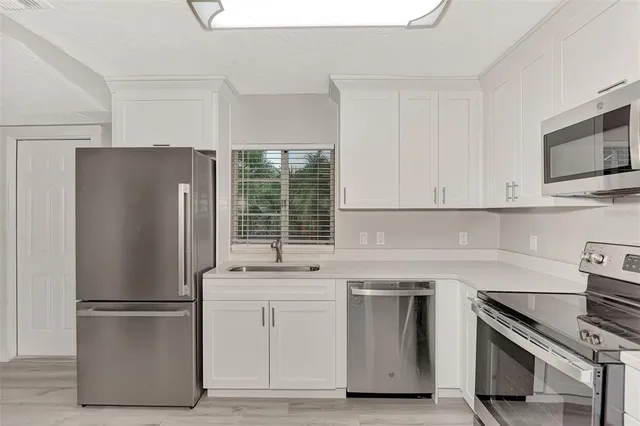 a kitchen with a refrigerator sink and cabinets