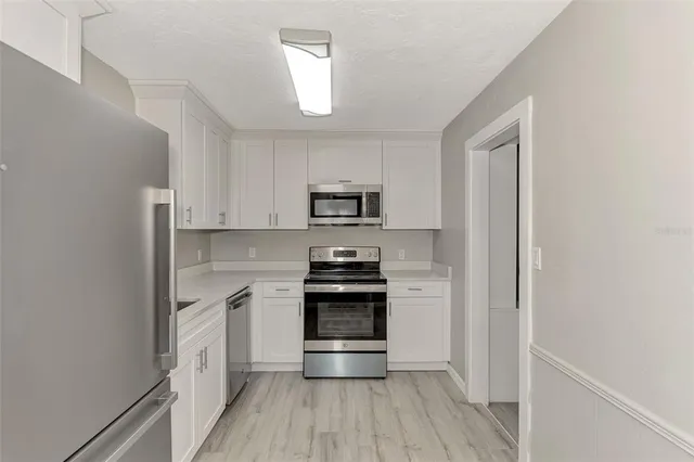 a kitchen with stainless steel appliances granite countertop white cabinets and a stove