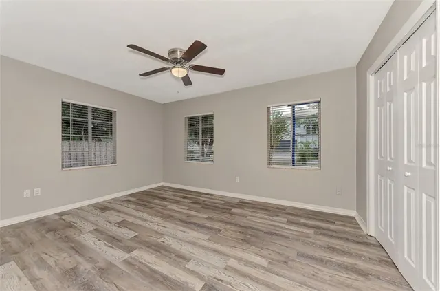 a view of empty room with wooden floor and fan