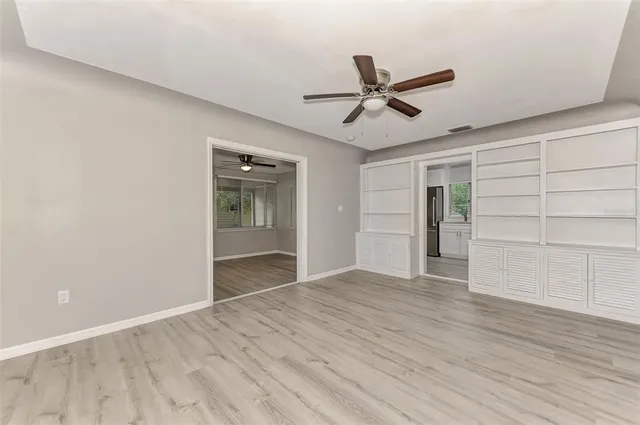 a view of empty room with wooden floor and fan