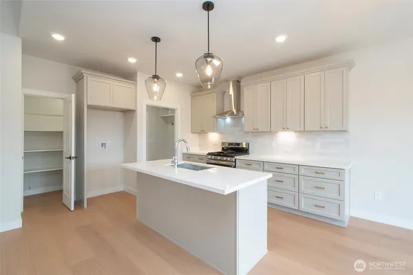 a kitchen with stainless steel appliances granite countertop a sink a stove a refrigerator and white cabinets