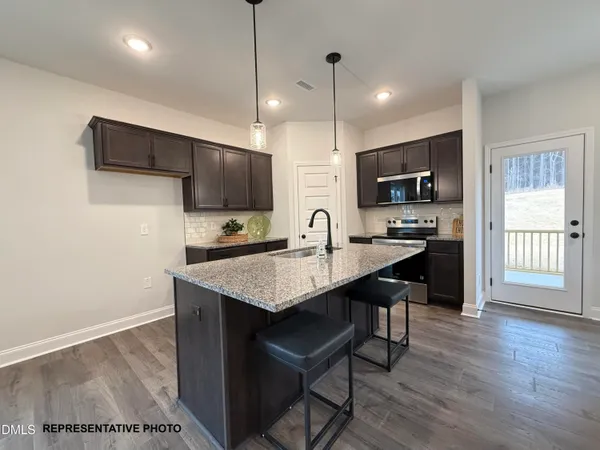 a kitchen with stainless steel appliances a sink a stove a refrigerator a center island and a wooden floor