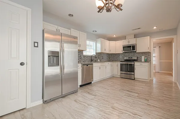 a kitchen with stainless steel appliances granite countertop a refrigerator a sink dishwasher a oven with white cabinets and wooden floor