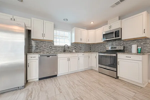 a view of a refrigerator in kitchen and an empty room with wooden floor