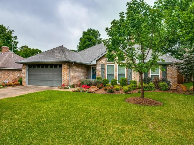 a front view of a house with a garden and trees
