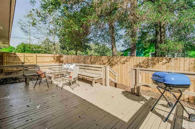 a view of a patio with table and chairs a barbeque with wooden floor and fence