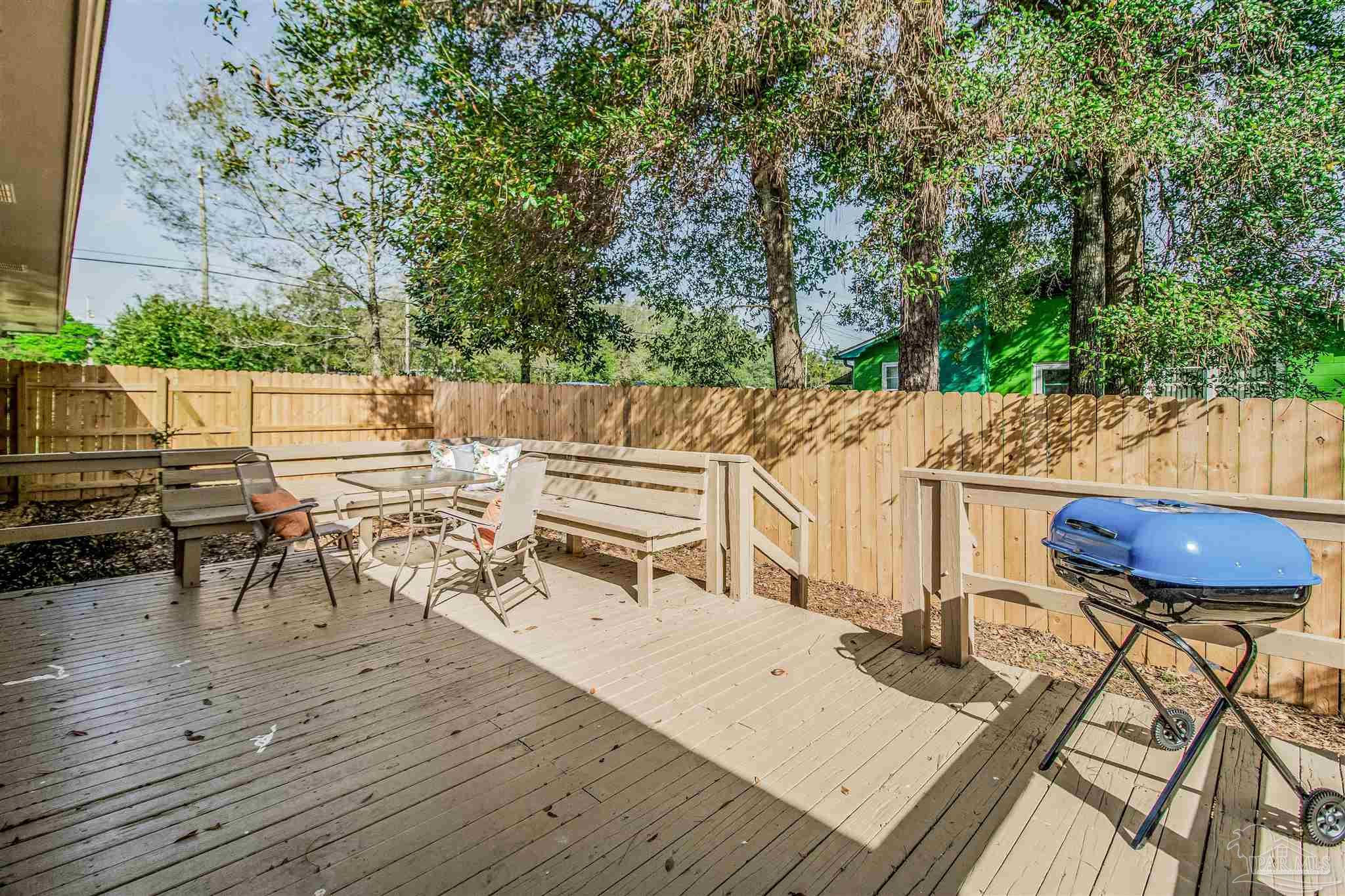 100 Mango Street Pensacola, FL 32503 - Photo 29 of 47 a view of a patio with table and chairs a barbeque with wooden floor and fence