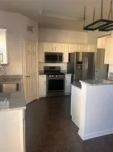 a kitchen with granite countertop a refrigerator and a stove top oven