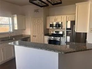 a kitchen with stainless steel appliances granite countertop a sink a stove and a refrigerator