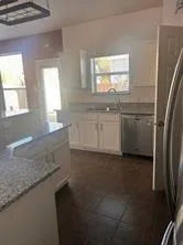 a kitchen with granite countertop white cabinets and white appliances