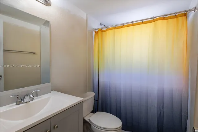 a bathroom with a sink a toilet and shower curtain