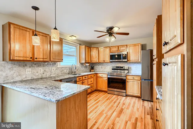 a kitchen with stainless steel appliances granite countertop a sink a stove and a wooden floors