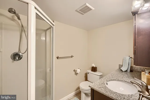 a bathroom with a granite countertop sink toilet and shower