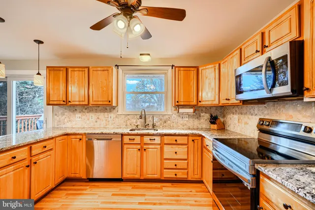 a kitchen with stainless steel appliances granite countertop a sink a stove cabinets and wooden floor