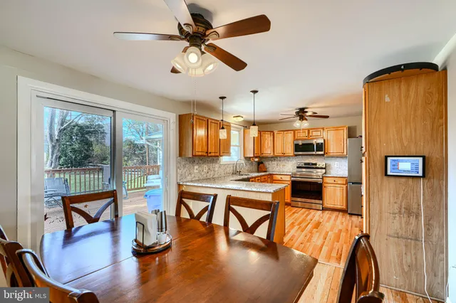 a living room with stainless steel appliances kitchen island granite countertop a table chairs and a view of kitchen