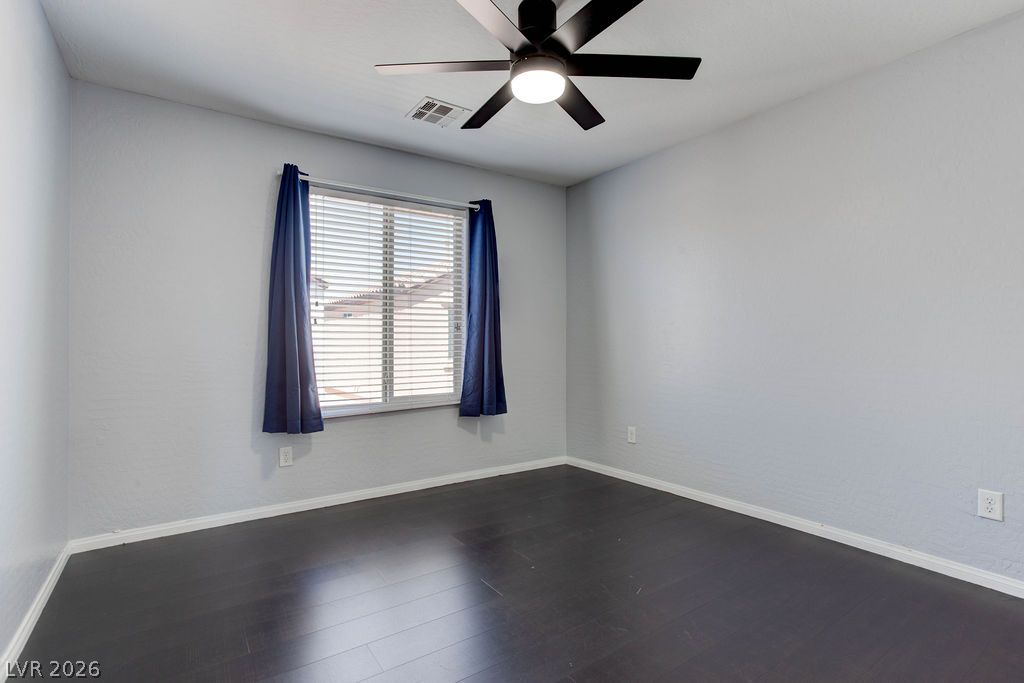 7724 Vibrant Thread Court Las Vegas, NV 89149 - Photo 27 of 43 An airy bedroom with dark wood flooring features a window with blinds and a modern ceiling fan.