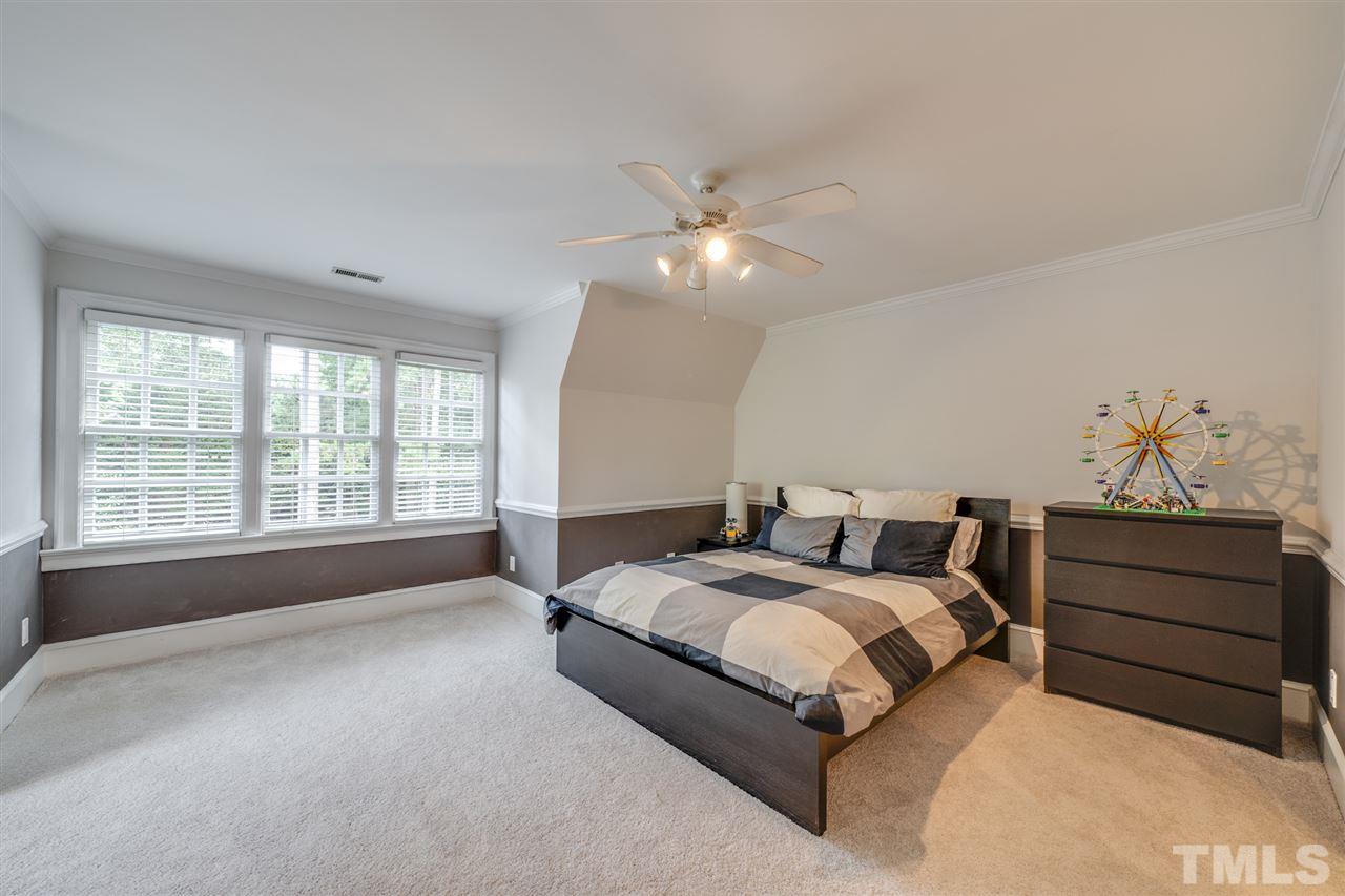 4621 White Chapel Way Raleigh, NC 27615 - Photo 18 of 30 a spacious bedroom with a large bed and a chandelier