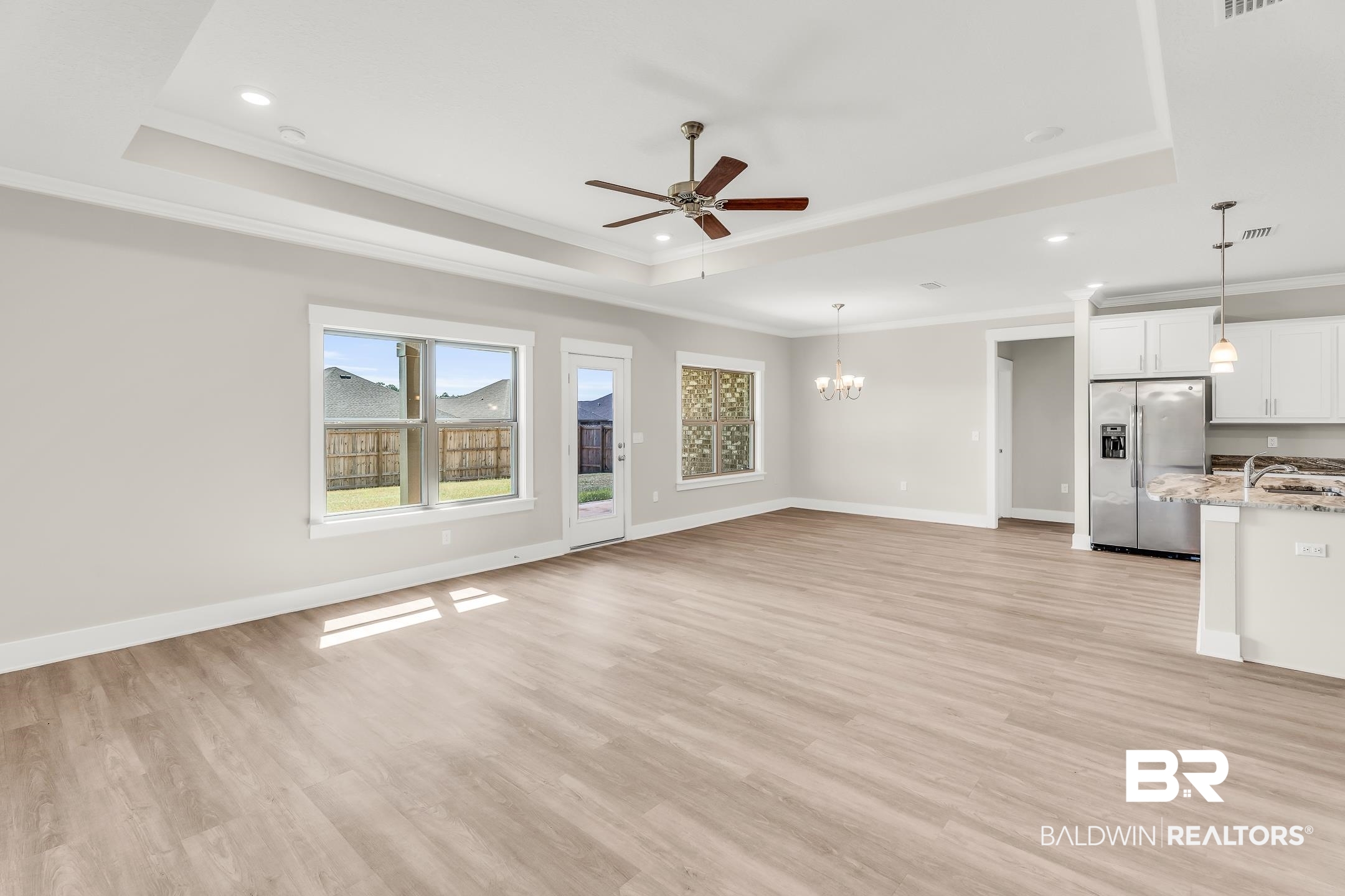 1720 Partridge Street Foley, AL 36535 - Photo 12 of 32 Unfurnished living room with ceiling fan with notable chandelier, light hardwood / wood-style floors, a raised ceiling, and ornamental molding