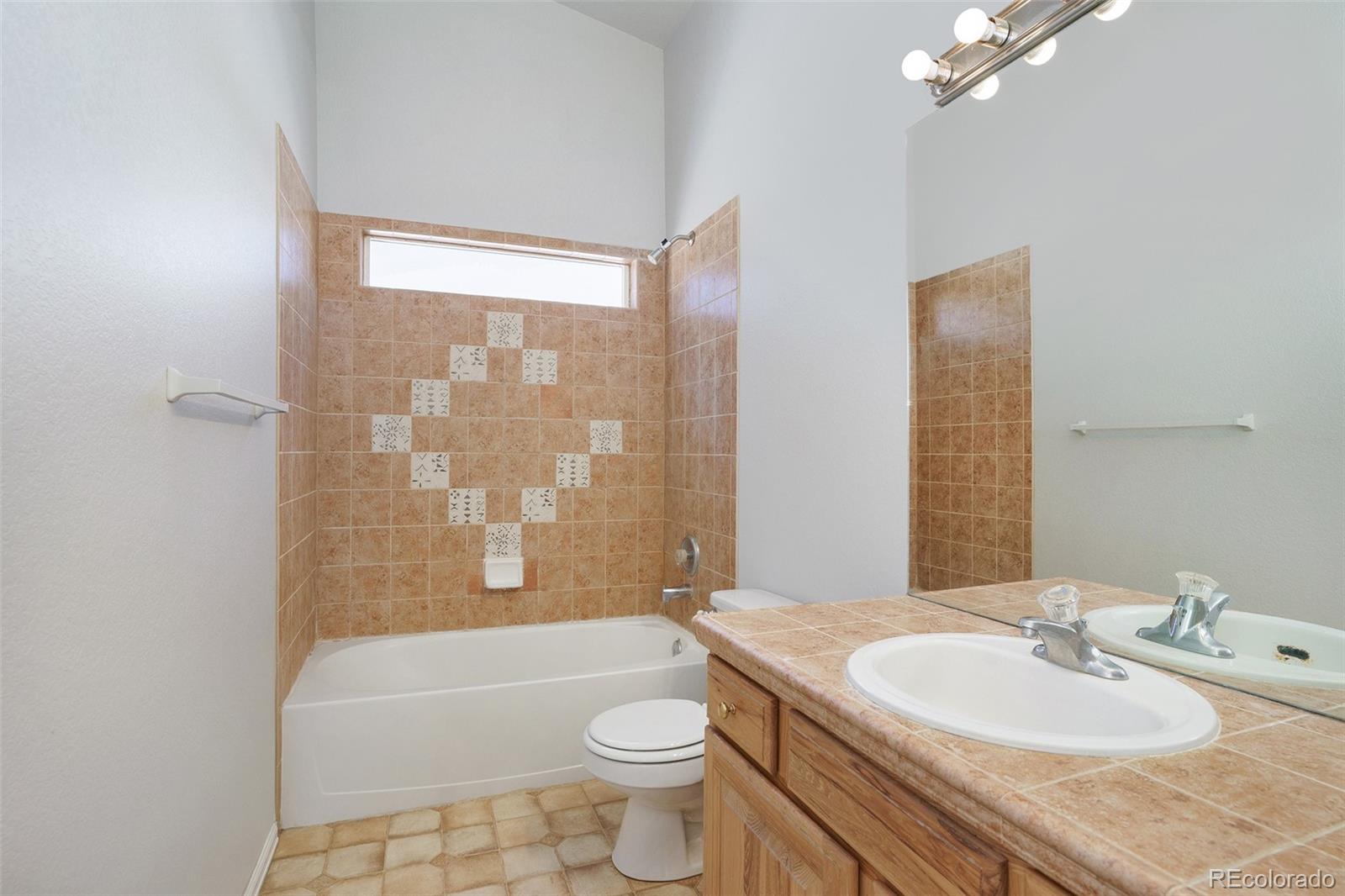 11949 Rio Secco Road Peyton, CO 80831 - Photo 13 of 19 a bathroom with a sink a toilet a mirror a bathtub and shower