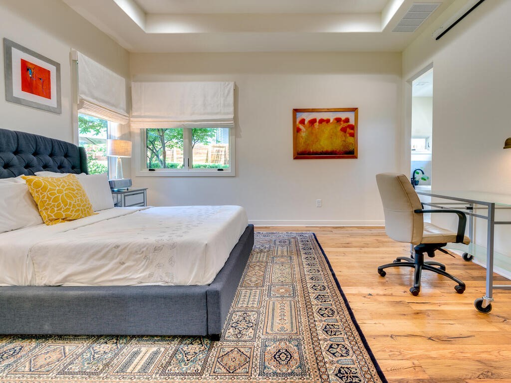 3907 Bailey Lane Austin, TX 78756 - Photo 18 of 37 The beautiful owner's suite is an oasis of peace and relaxation with calming, neutral toned walls, beautiful views from the windows, and light fixtures that put off soft illumination