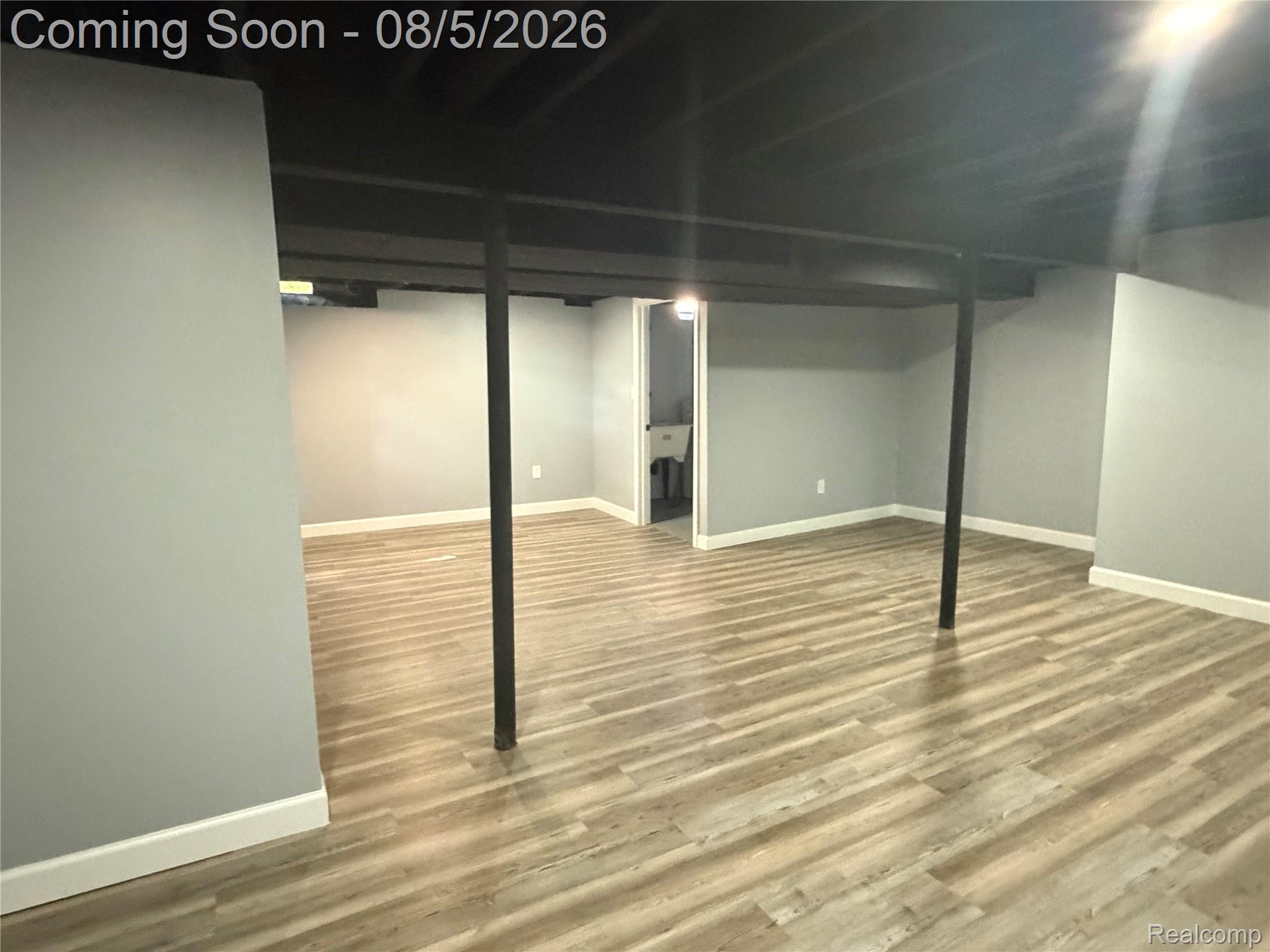 20698 Coachwood Road Riverview, MI 48193 - Photo 16 of 37 Finished lower level featuring wood-finish flooring, painted gray walls, white baseboards, and an exposed black ceiling with structural beams