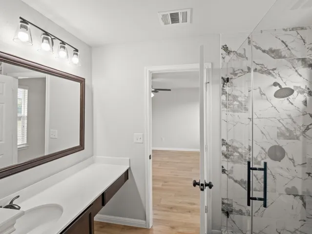 a bathroom with a sink vanity and shower